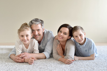 Portrait of cheerful family laying on carpet