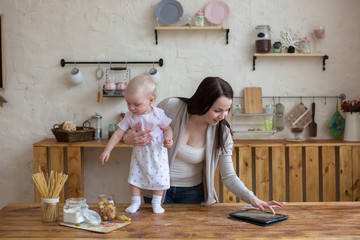 Mom and daughter playing together with tablet in home interior l