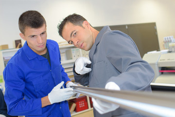 Obraz premium Two men looking down the length of a metal pole