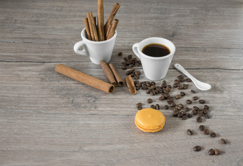 A cup of coffee  with cinnamon and macaroon