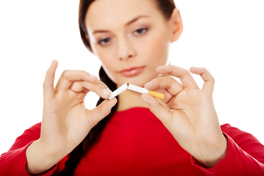 Unhappy young woman holding broken cigarette