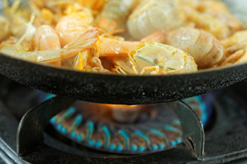 Silver Mantis Shrimp and Prawn cooked in the wok. Upper half picture showing shrimp and prawn inside the wok and below half picture showing the gas stove.In the middle of cooking process.