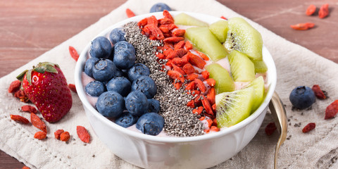 Smoothie bowl with strawberry smoothie, berries, kiwi and chia