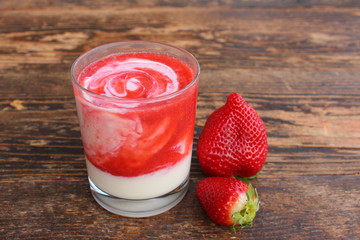 Gesunder Erdbeershake mit Joghurt auf Holztisch
