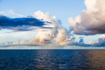 Naklejka na ściany i meble Blue ocean, light of large clouds reflected on surface, rainbow