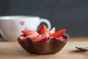 Erdbeerwaffel als Nachtisch mit Löffel und Tasse auf Holzbrett