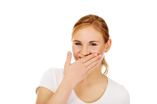 Young woman giggles covering her mouth with hand