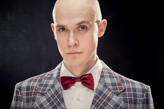 Young alluring bald caucasian man professor or teacher with red bow tie black isolated