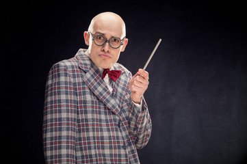 bald caucasian professor or teacher with bow and glasses tie point stick on blackboard with copy space