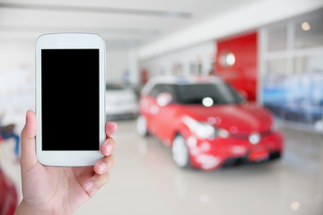 hand holding mobile phone with cars in showroom