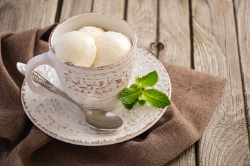 Vanilla ice cream in cup on rustic wooden background, selective focus, copy space