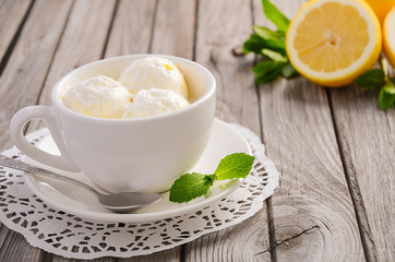 Lemon ice cream in white cup on rustic wooden background, selective focus, copy space