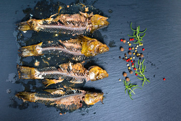 top view of fish skeleton bones and flavor peppers on slate background, close up