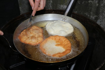 Cook hands while cooking the fried fritters dipped in boiling oi