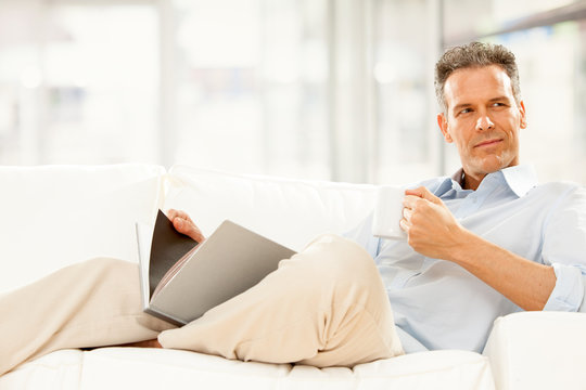 handsome businessman read and drink cup of tea on the couch at home