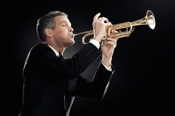 handsome businessman play trumpet isolated on black