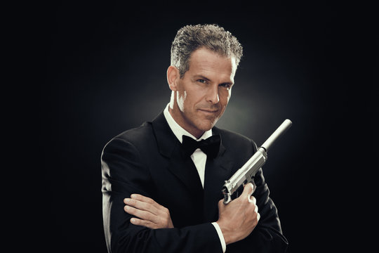 elegant man with bow tie and gun isolated on black