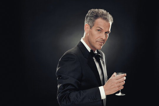 handsome businessman drink martini isolated on black