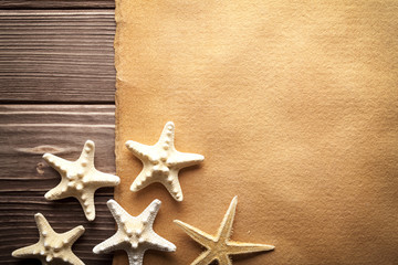 Fototapeta na wymiar Starfishes and blank handmade paper sheet on wooden table