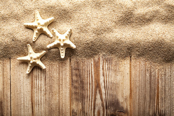 Fototapeta na wymiar Three starfishes on sand and wooden planks