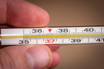 thermometer in hand on the background of pills