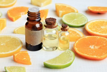 Essential oils set, orange, lime, lemon. Aroma bottles, fruit slices. 