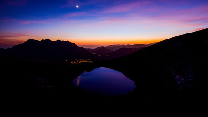 beautiful mountain landscape at sunset with moon and little lake