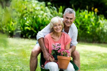 Happy senior couple with flower pots in yard 