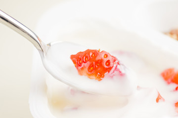 close-up of healthy strawberry and white yogurt on the spoon