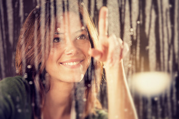romantic young woman looks at rain through the window