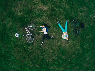 Fototapeta premium Young couple lying on the grass and biking, top view, a general