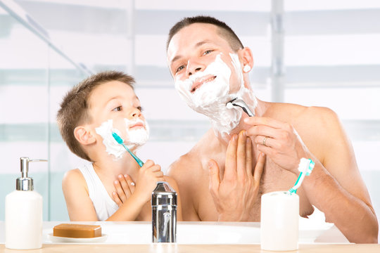 happy child have fun with dad with shaving foam in the bathroom