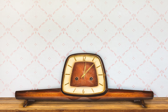 Vintage table clock in front of retro wallpaper