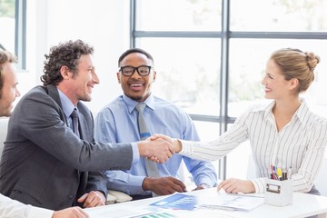 Businessman shaking hands with businesswoman in meeting