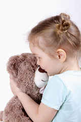 little blond girl hugging a teddy bear