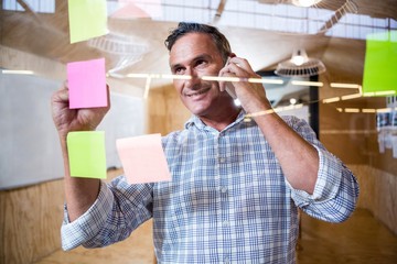 Man writing on sticky notes while talking on phone