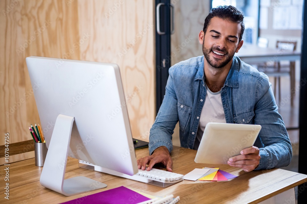 Poster Happy man looking at digital tablet while using computer