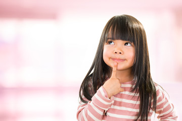 asian smiling little thoughtful girl isolated on pink