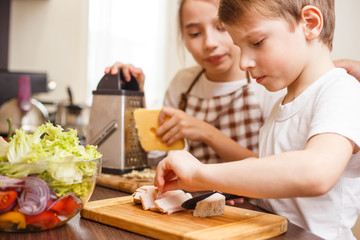 Obraz na płótnie Canvas Small boy with his sister preparing food together