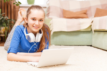 Teenage smiling girl using laptop on the floor