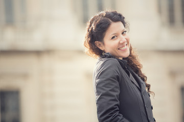 smiling curly woman in cityscape