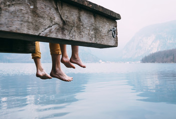 Father and son swung their legs from the wooden pier on mountain