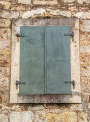 Окно на фасаде каменной стены здания в старом городе Черногории 