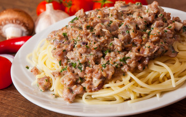 spaghetti with mushroom and minced meat in a plate on wooden table