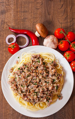 spaghetti with mushroom and minced meat in a plate on wooden table