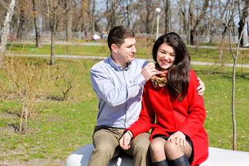 Happy young family spending time outdoors in a park on a spring day with blue sky in background. Spending time together having fun and smiling. Married couple. 