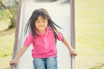 happy asian smiling child play with slide in a park