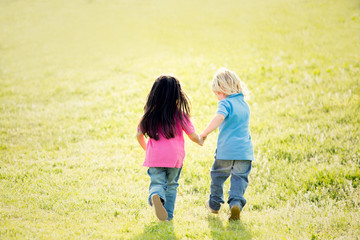 couple of interracial children play together in a garden