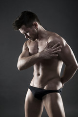 Fototapeta premium Handsome muscular bodybuilder posing on gray background. Low key studio shot