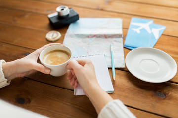 close up of hands with coffee cup and travel stuff